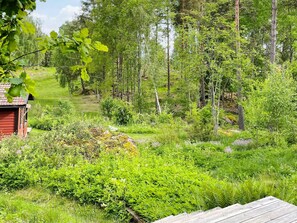A forested area with a red building, likely a cabin, surrounded by dense greenery and trees. - 5 Person Holiday Home in Mellosa (Flen)