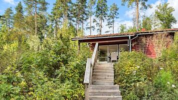 A wooden staircase leading to a red-roofed building surrounded by dense greenery and tall trees.