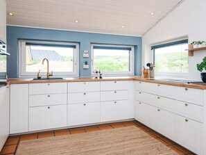 A kitchen with white cabinets, a wooden countertop, and a window with a view of greenery. - 4 Star Holiday Home in Hvide Sande (Hvide Sande)