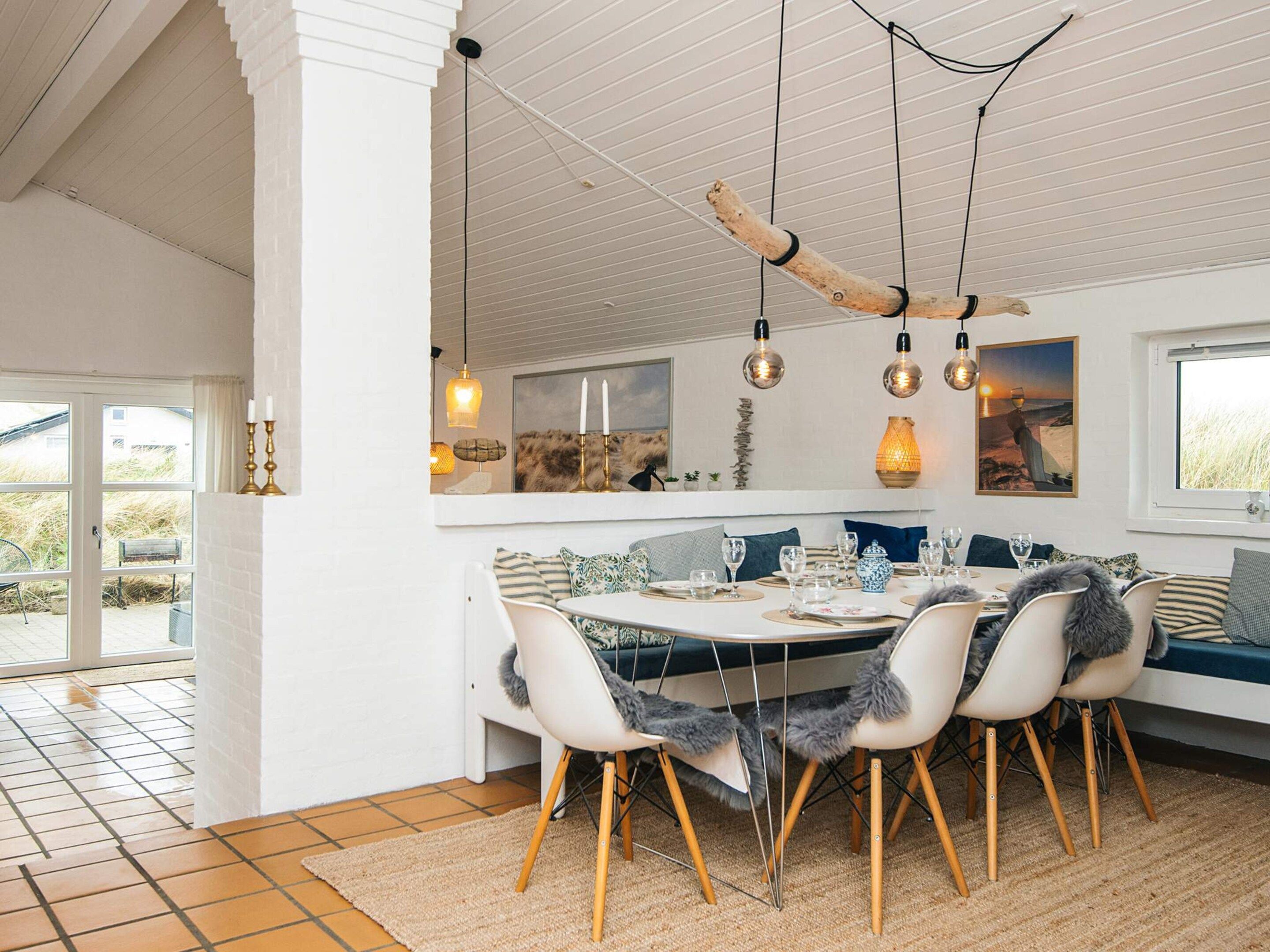A dining area with a round table, chairs, and hanging pendant lights.