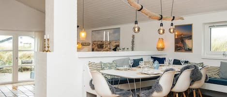 A dining area with a round table, chairs, and hanging pendant lights.