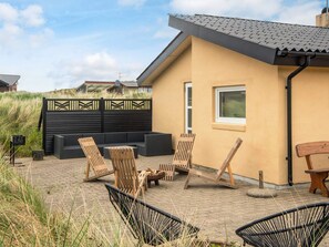 A patio with outdoor furniture, a black fence, and a building with a window. - 4 Star Holiday Home in Hvide Sande (Hvide Sande)