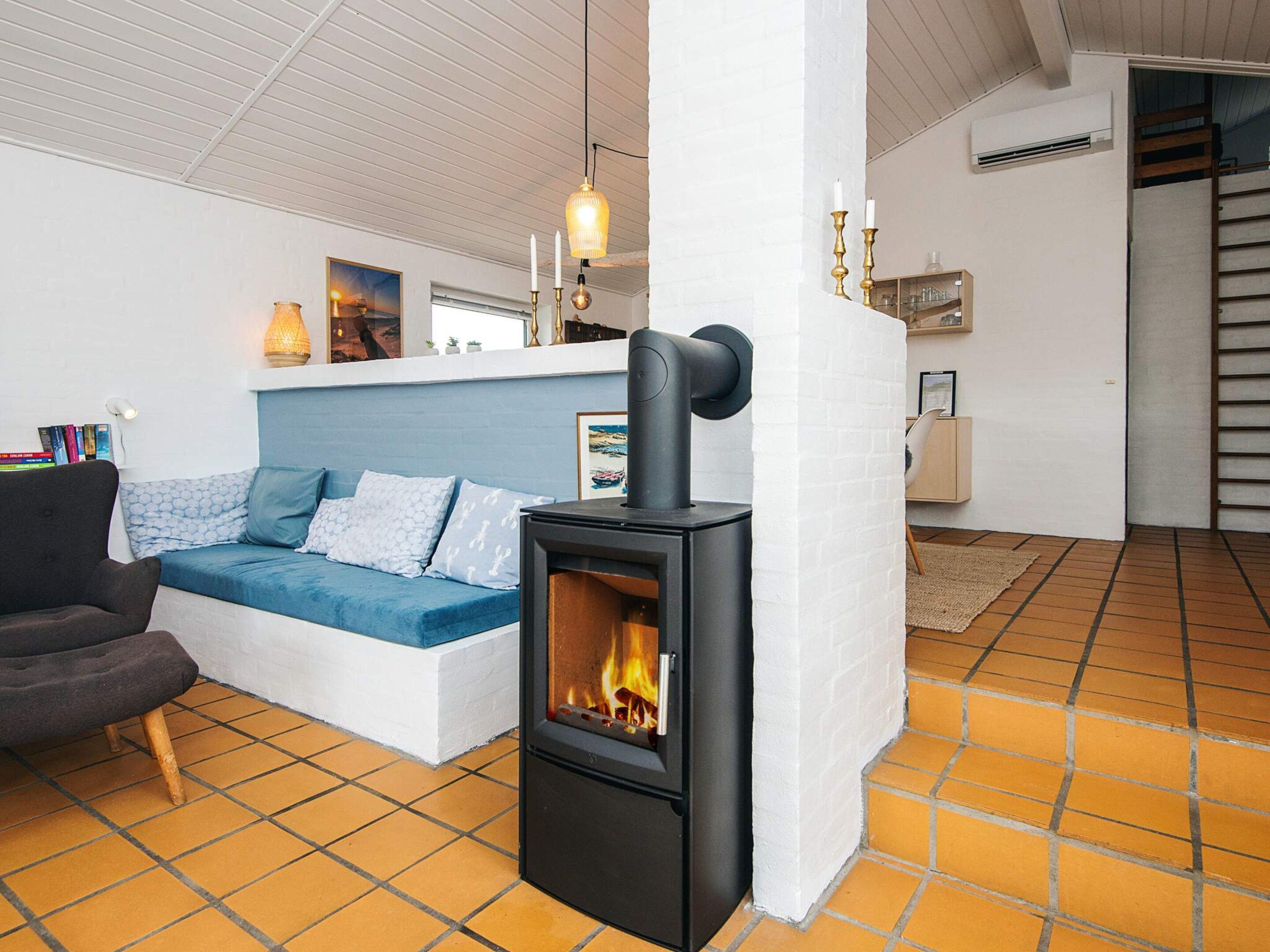 A cozy living area with a sofa, a black wood-burning stove, and a white brick wall.