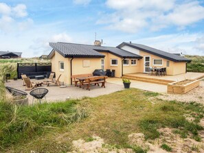 A two-story house with a patio area, outdoor seating, and a small deck. - 4 Star Holiday Home in Hvide Sande (Hvide Sande)