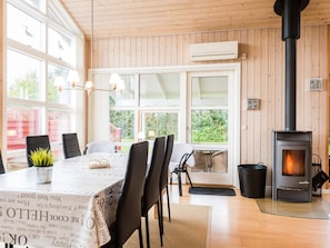 A cozy room with a dining table, chairs, a fireplace, and large windows.