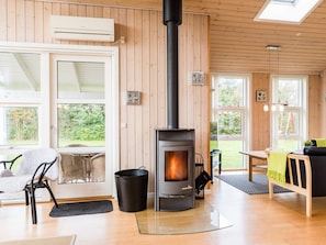 A cozy room with a wood-burning stove, a dining area, and large windows. - 4 Star Holiday Home in Tarm (Tarm)