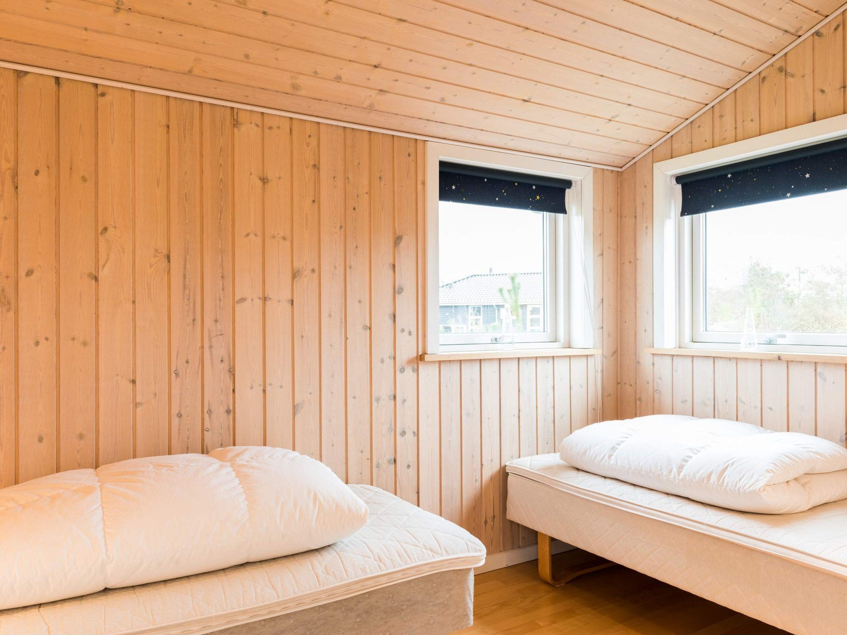 A room with wooden walls and two beds with white bedding.