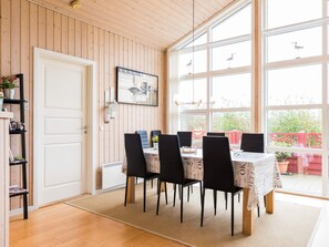 A dining area with a table set for four, surrounded by chairs, with a view of the outside through large windows. - 4 Star Holiday Home in Tarm (Tarm)