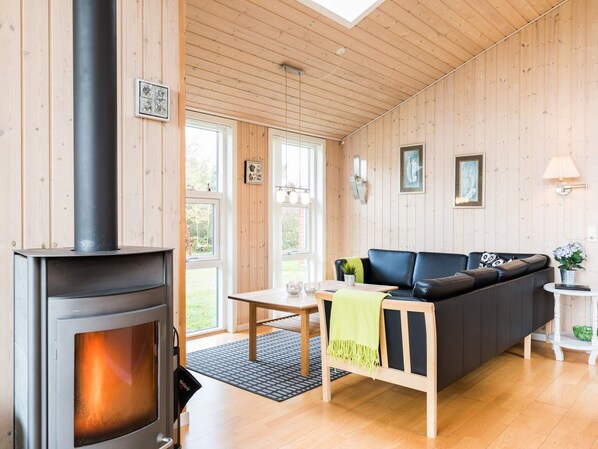 A cozy living room with a wood-burning stove, a sofa, a small table, and a window.