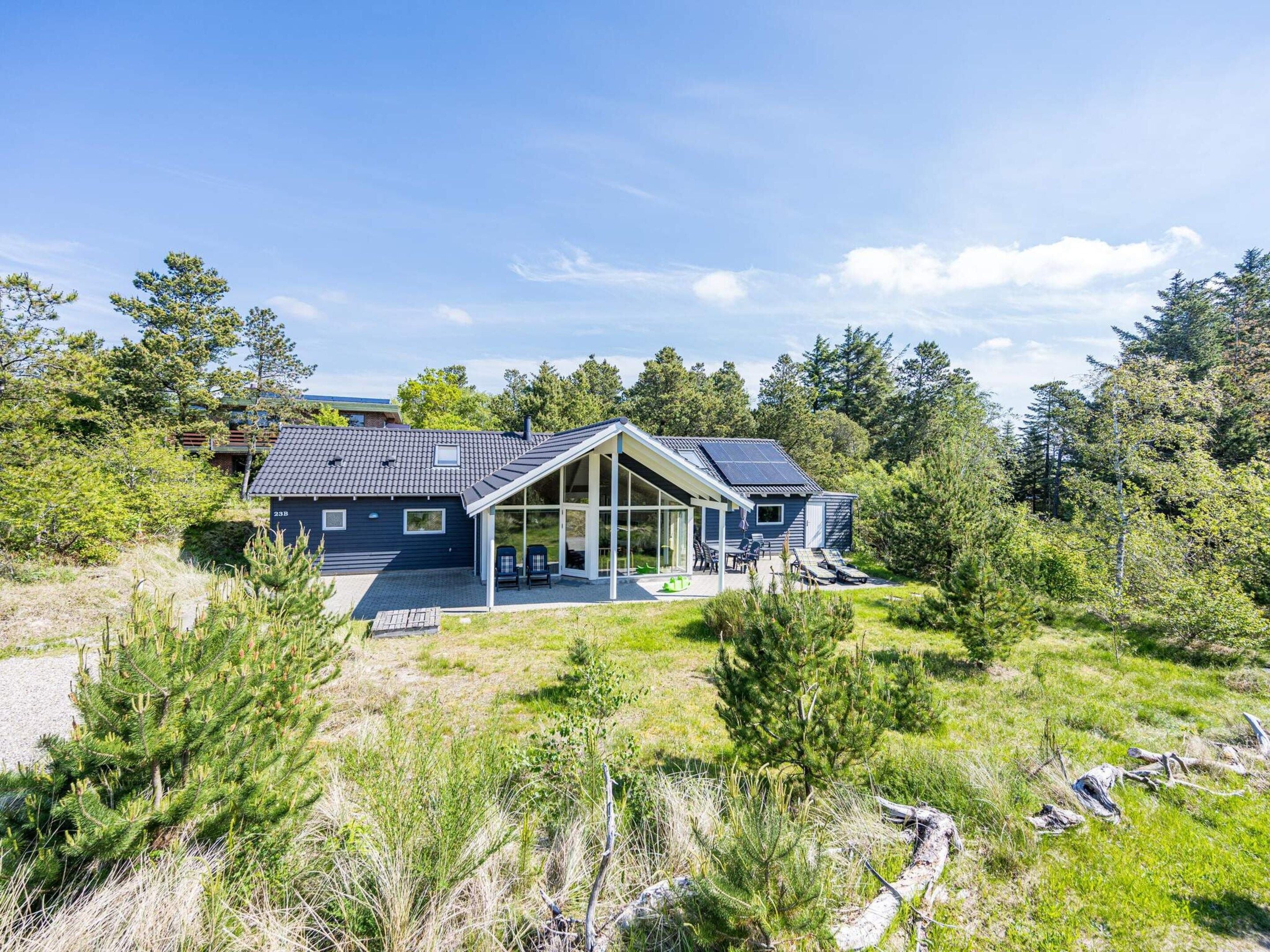 A modern house with a large glass extension, surrounded by a natural landscape.