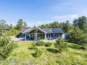 A modern house with a covered patio, solar panels, and a well-maintained lawn. - 5 Star Holiday Home in Norre Nebel (Norre Nebel)