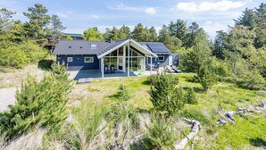 Una casa moderna con un amplio ventanal, rodeada de un paisaje natural.