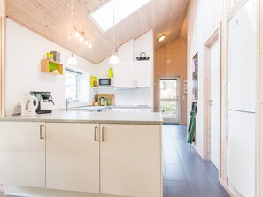 A modern kitchen with white cabinets, a coffee machine, and a window. - 5 Star Holiday Home in Norre Nebel (Norre Nebel)