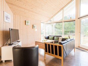 A modern interior with wooden panel walls, a sofa, a desk, and a television.