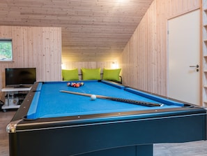 A pool table with balls and a cue stick, a television on a stand, and a door with a keyhole. - 5 Star Holiday Home in Norre Nebel (Norre Nebel)