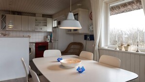 A kitchen with white cabinets, a red stove, and a dining area with a white table and chairs. - 6 Person Holiday Home in Fano (Fano)