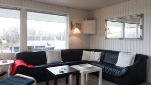 A modern living room with a black leather sofa, white tables, and a large window with a view of the outdoors. - 6 Person Holiday Home in Fano (Fano)