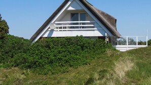 A triangular house with a thatched roof, a balcony, and a view of the surrounding greenery. - 6 Person Holiday Home in Fano (Fano)