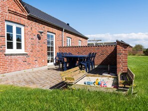 A brick house with a patio, a table with chairs, and a wooden bench. - 4 Star Holiday Home in Tarm (Tarm)