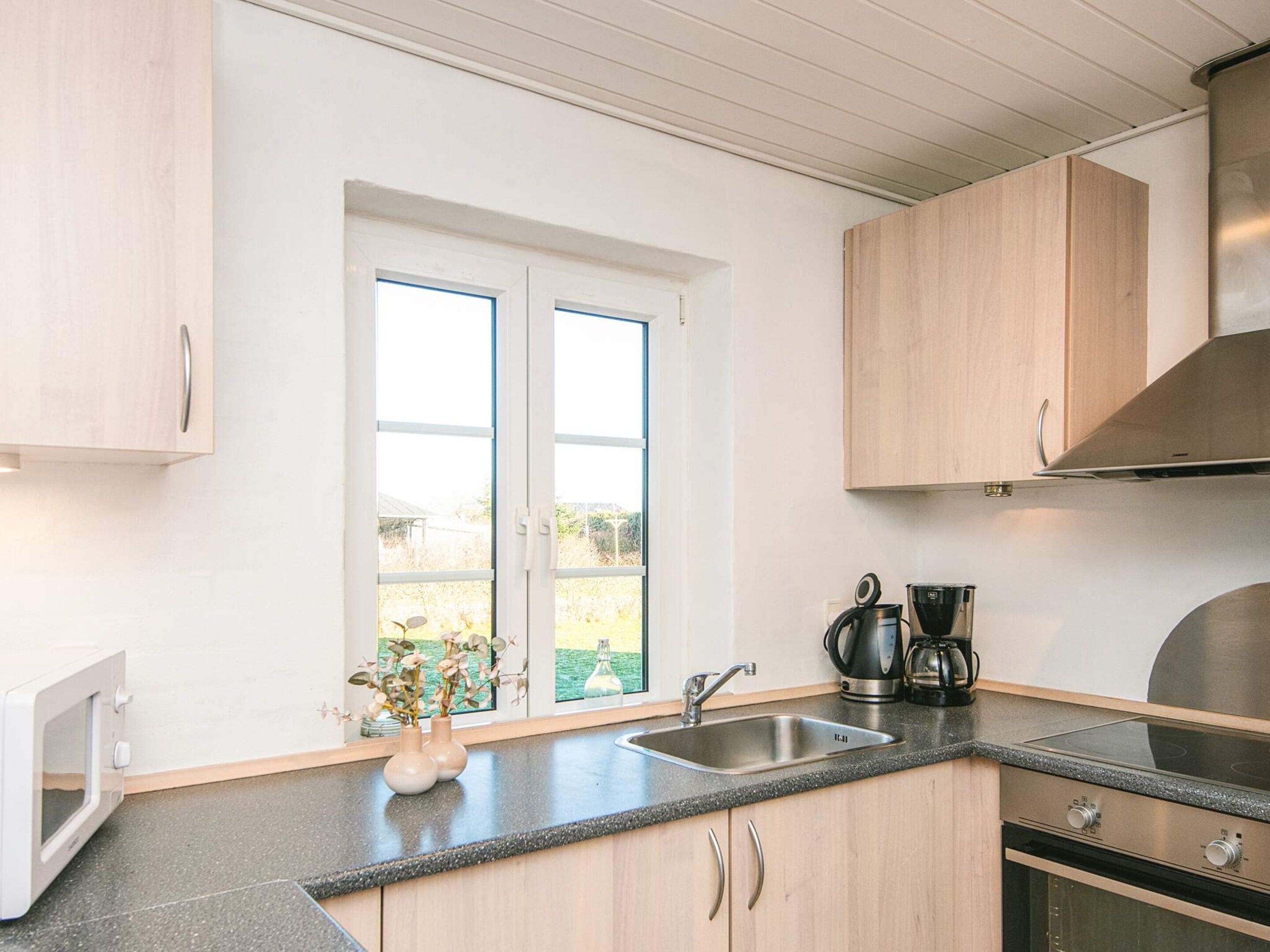 Eine moderne Küche mit einem Fenster mit Zweifachverglasung, Edelstahlgeräten und Holzschränken.