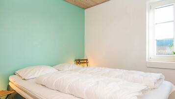 A bedroom with a bed, a window, and a wooden ceiling.