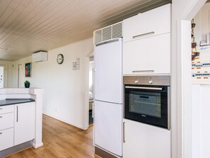 A modern kitchen with white cabinetry, a built-in oven, and a clock on the wall. - 4 Star Holiday Home in Henne (Henne)