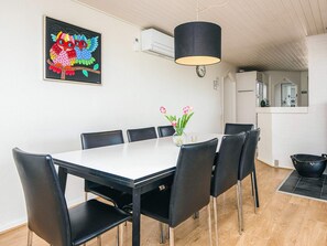 A dining area with a white table, black chairs, a vase with pink flowers, and a colorful owl painting on the wall.