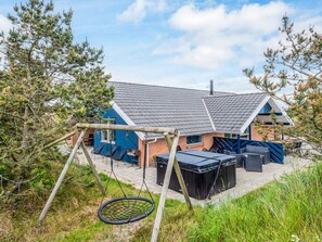 A house with a patio, outdoor seating, and a swing set. - 4 Star Holiday Home in Henne (Henne)