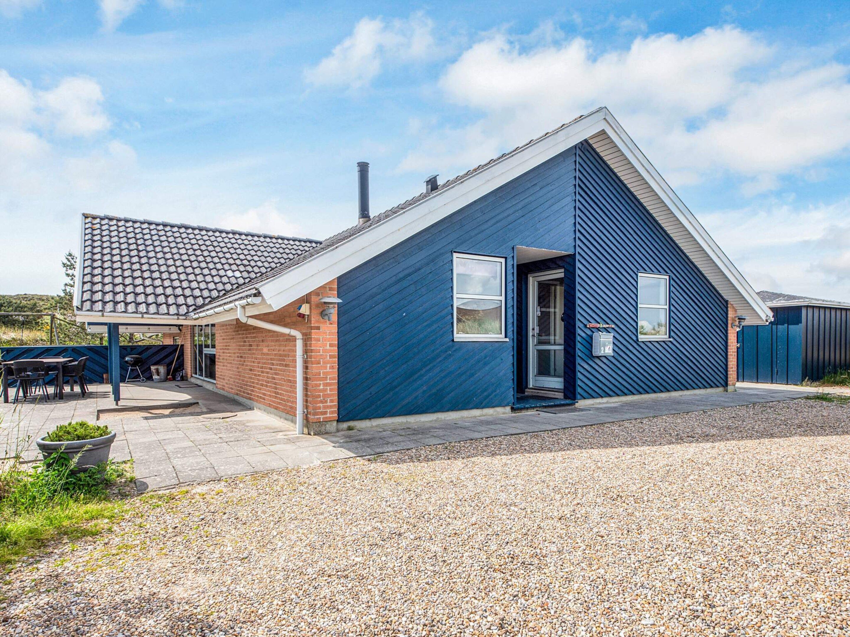 A modern house with a sloped roof, a brick exterior, and a gravel driveway.