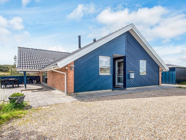 A modern house with a sloped roof, a brick exterior, and a gravel driveway.