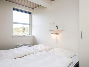 A bedroom with a bed, a window, a wall-mounted shelf with a plant, and a wall-mounted light fixture. - 4 Star Holiday Home in Henne (Henne)