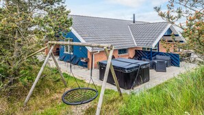 A house with a patio area, a swing set, and outdoor seating.