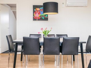 A dining area with a rectangular table, six black chairs, a vase with pink tulips, and a colorful owl painting on the wall. - 4 Star Holiday Home in Henne (Henne)