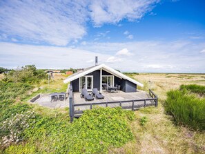 Een modern huis met een ruim terras, een overdekt buitengebied en uitzicht op het omliggende landschap.