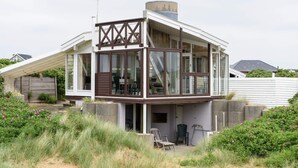 Uma casa moderna com uma grande janela de vidro, um deck de madeira e uma parede de concreto.