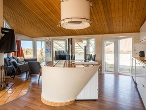 A modern interior with a central island, wooden flooring, and a sloped ceiling.