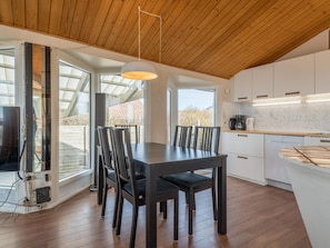 A modern kitchen with white cabinets, a wooden dining table, and chairs.