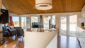 Cozinha moderna com ilha central, teto de madeira e grandes janelas.
