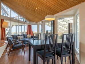 A modern interior with a dining area, seating, and large windows offering views.