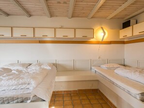 Un dormitorio con dos camas, techo de madera y una lámpara fijada a la pared.