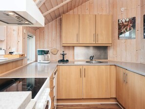 Una cocina moderna con armarios de madera, una cafetera y un lavamanos.
