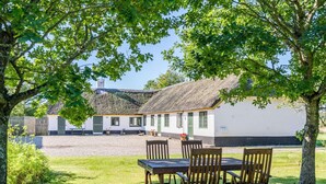 A rustic thatched-roof building with a gravel courtyard and wooden furniture. - 4 Person Holiday Home in Norre Nebel (Norre Nebel)