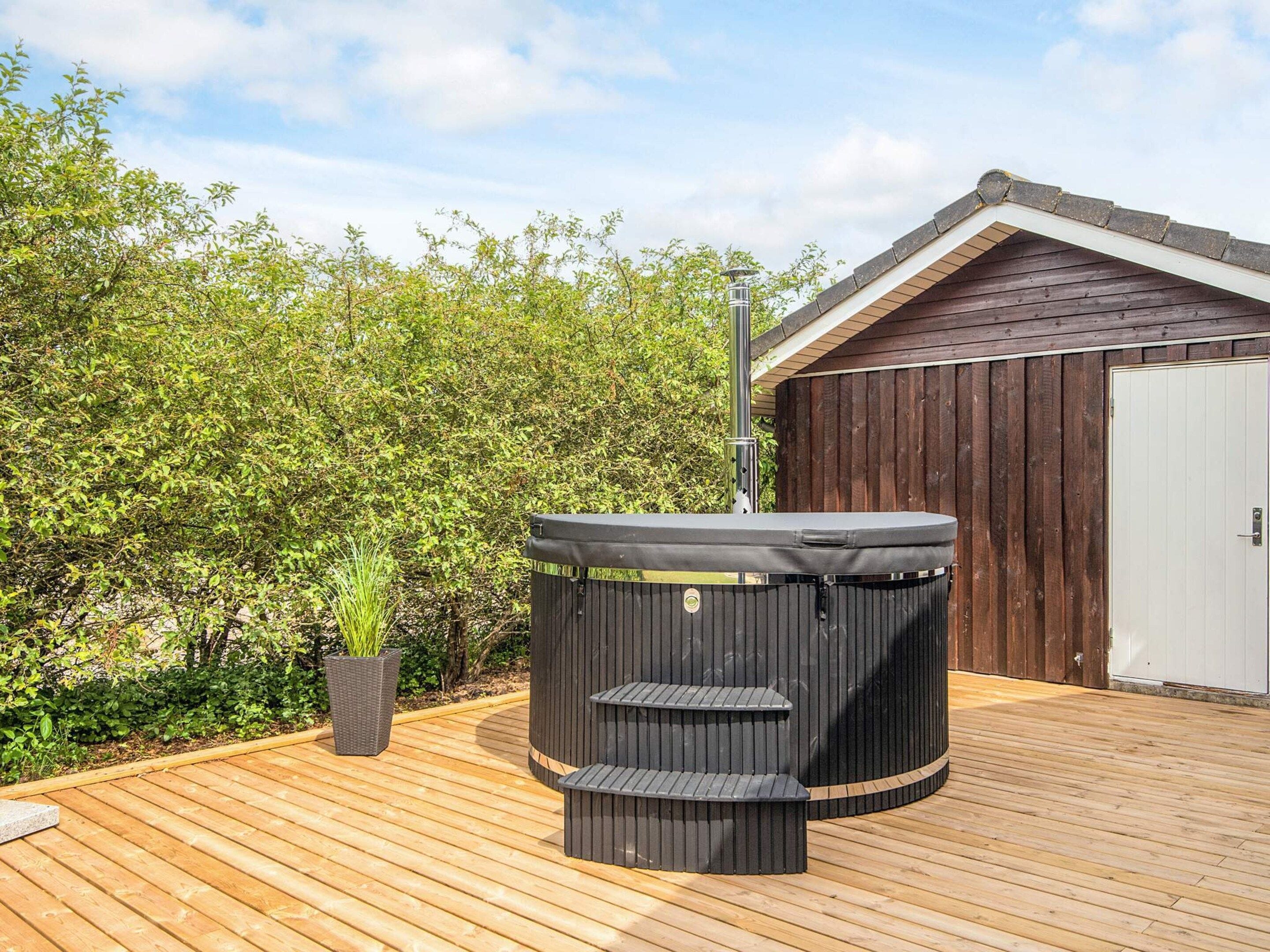 Ein Whirlpool mit Stufen, eine Holzterrasse und ein Holzgebäude im Hintergrund.