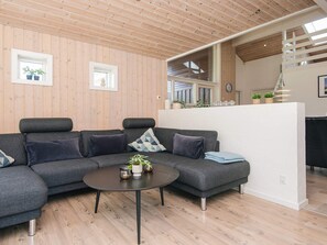 En moderne stue med en modulsofa, et rundt sofabord og trægulv.