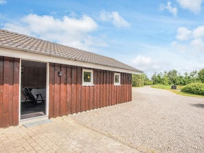 A wooden building with a gravel driveway and a clear sky.