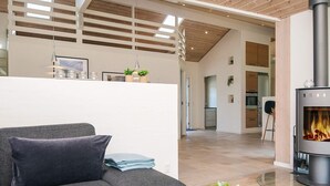 Una sala de estar moderna con un sofá gris, una mesa de centro de vidrio y una estufa de leña.