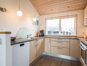 A modern kitchen with a dishwasher, sink, and stove. There is a window providing natural light and a view outside. - 5 Star Holiday Home in Tarm (Tarm)