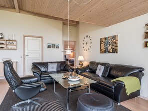 A modern living room with a glass coffee table, leather sofas, and a black leather armchair. - 5 Star Holiday Home in Tarm (Tarm)