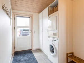 Ett tvättrum med tvättmaskin, torktumlare och en liten hylla i trä.