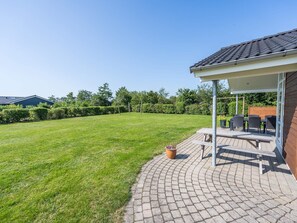 A patio with outdoor furniture, a brick pathway, and a well-maintained lawn. - 5 Star Holiday Home in Tarm (Tarm)